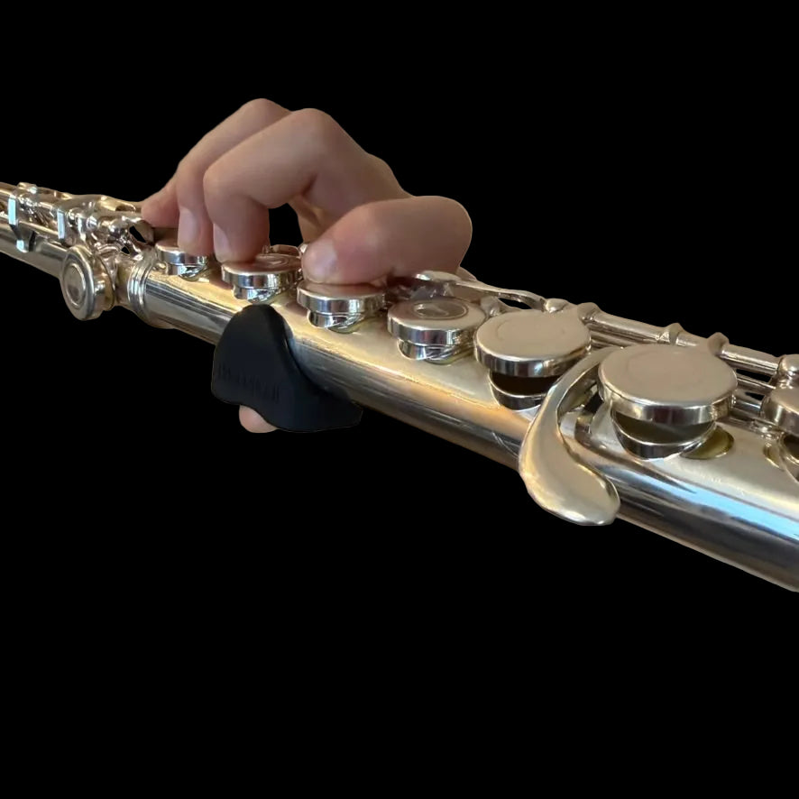 Close-up of a person playing a silver flute with a thumb gummi installed