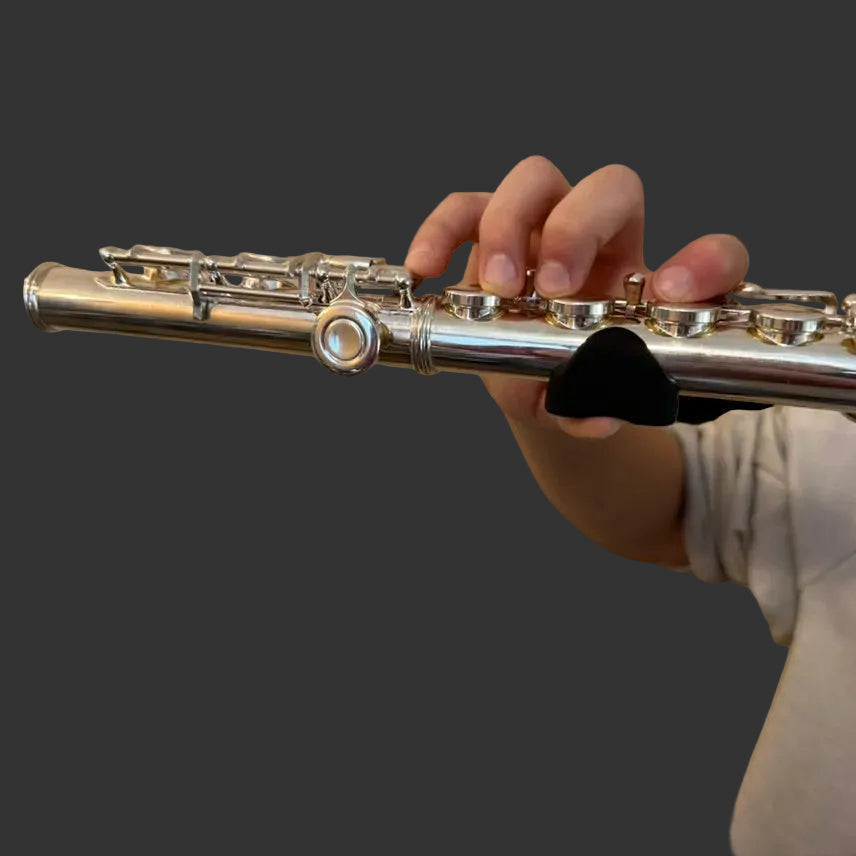 Hand holding a silver flute with a thumb gummi installed